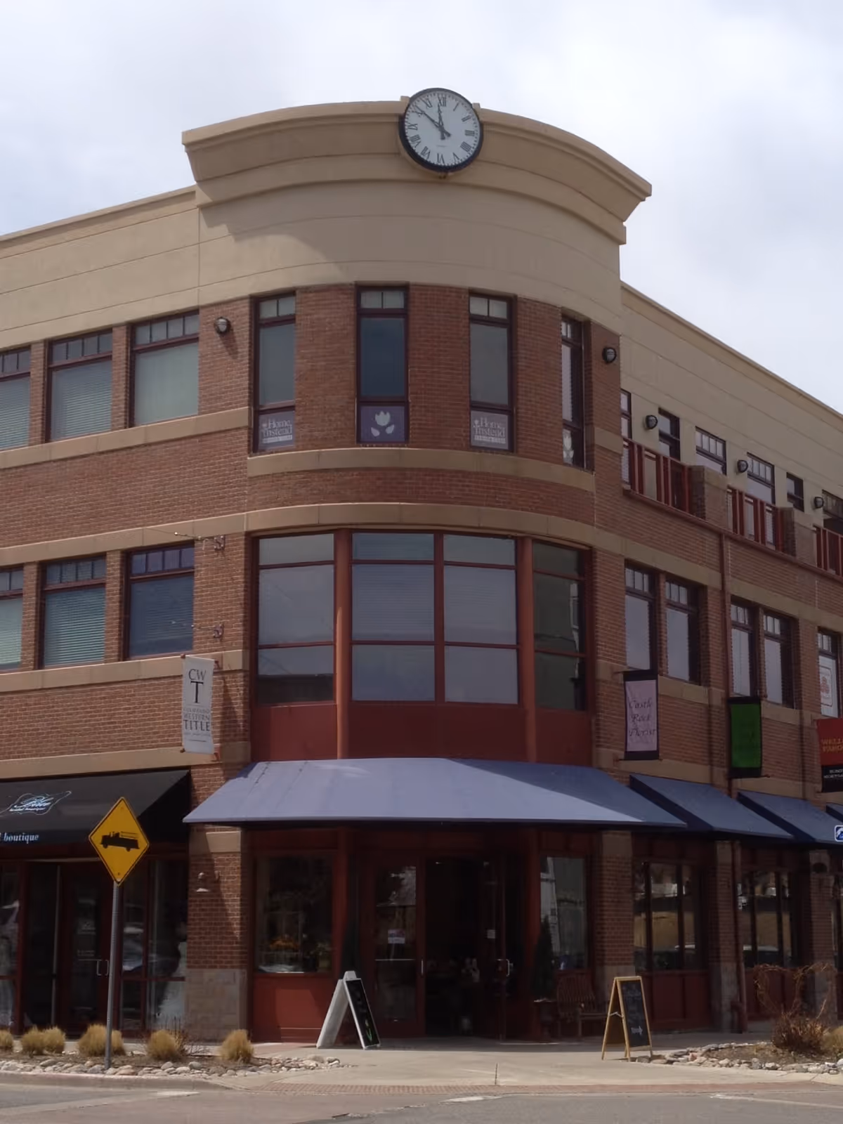Exterior view of a brick building with a clock atop its curved corner.