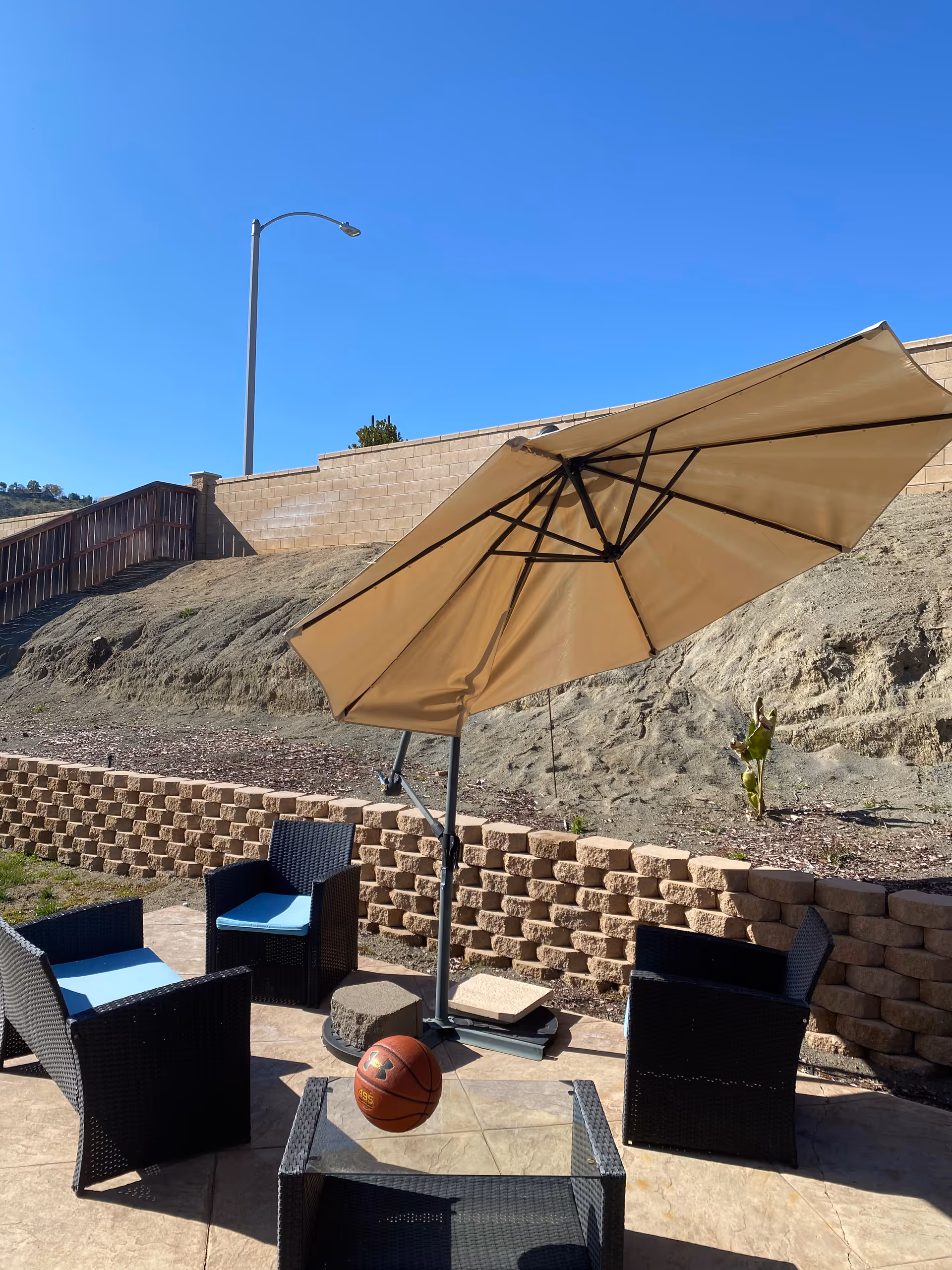 Outdoor patio area with wicker chairs, a large umbrella, and a basketball.