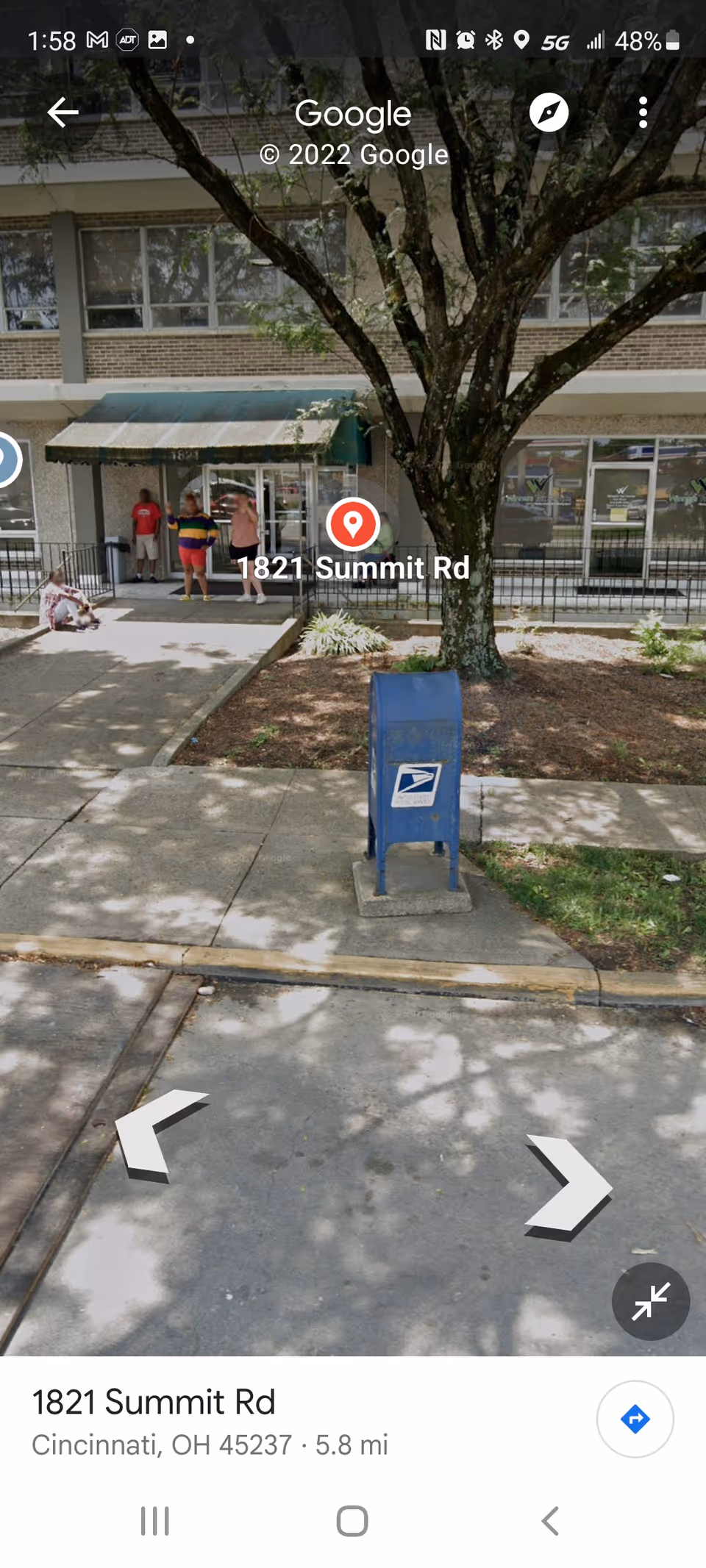 Outside building entrance with people, a blue USPS mailbox, and a tree.