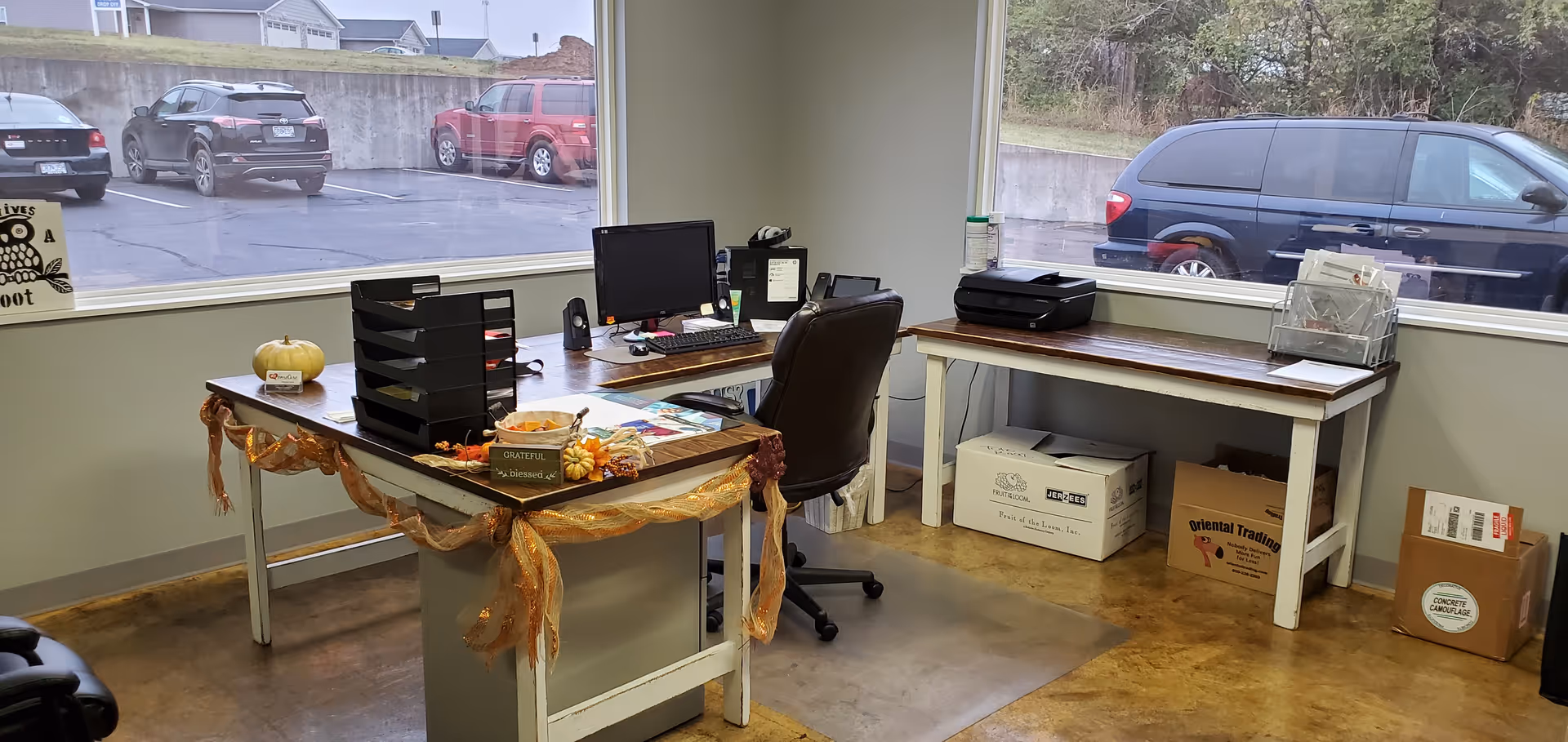 Office workspace with desk, computer, printer, files, and large windows.