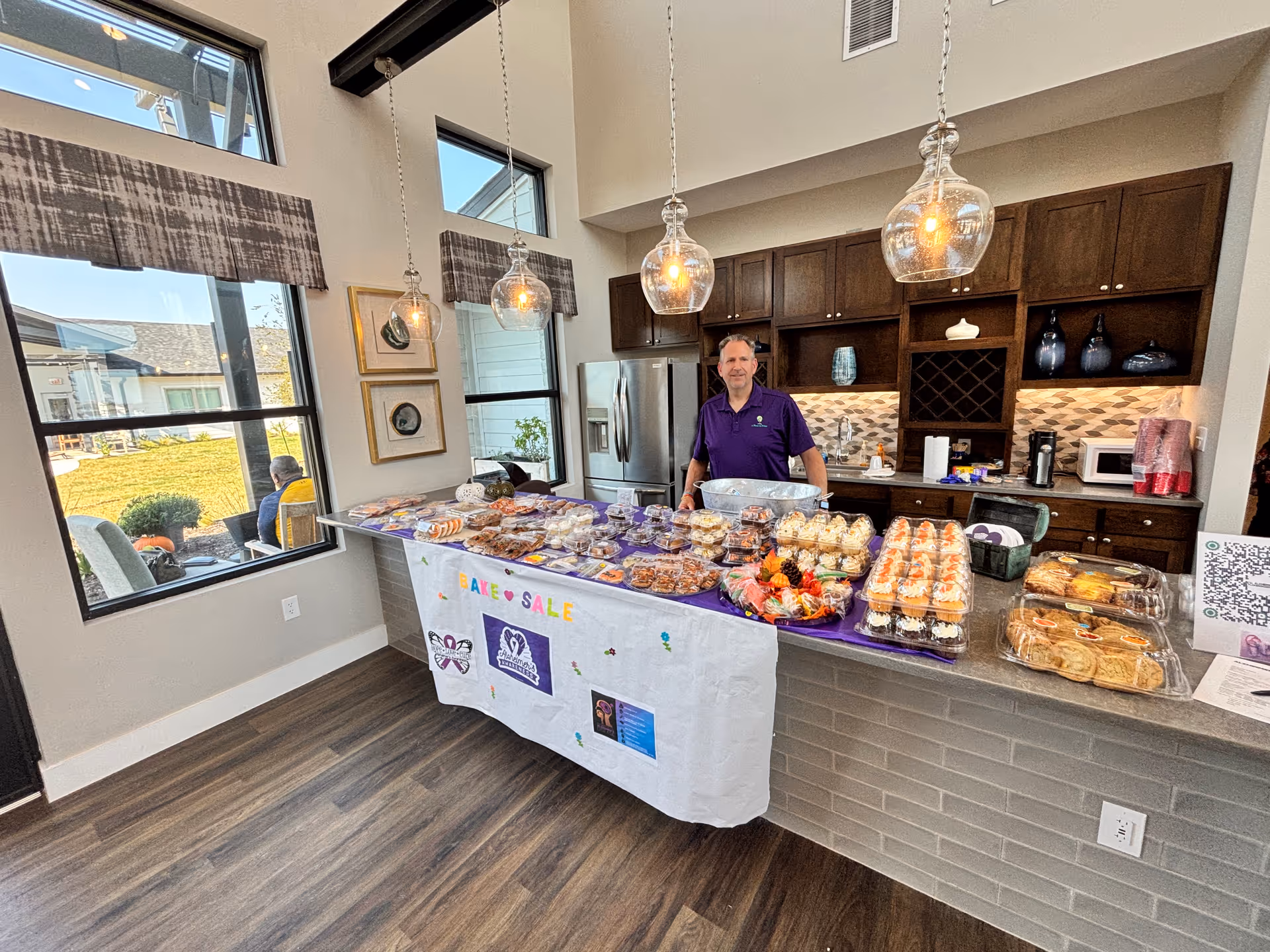 Staff member behind a bake sale table in a bright, modern kitchen.