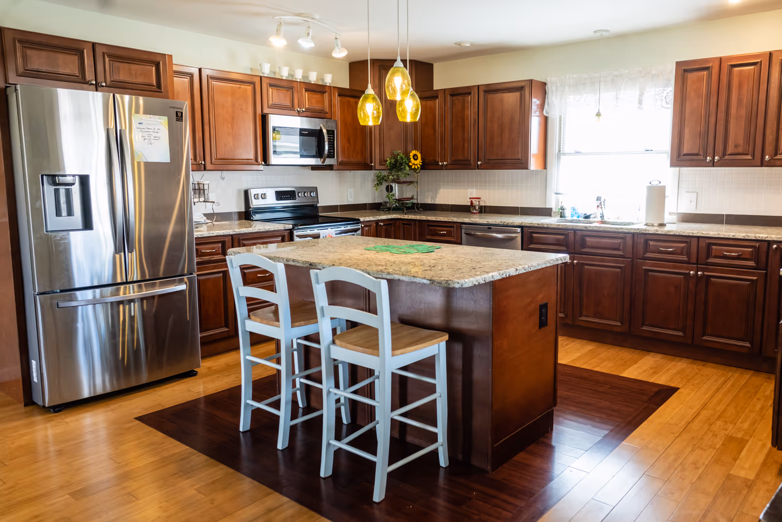 A modern kitchen with dark wood cabinets, stainless appliances, and a central island.