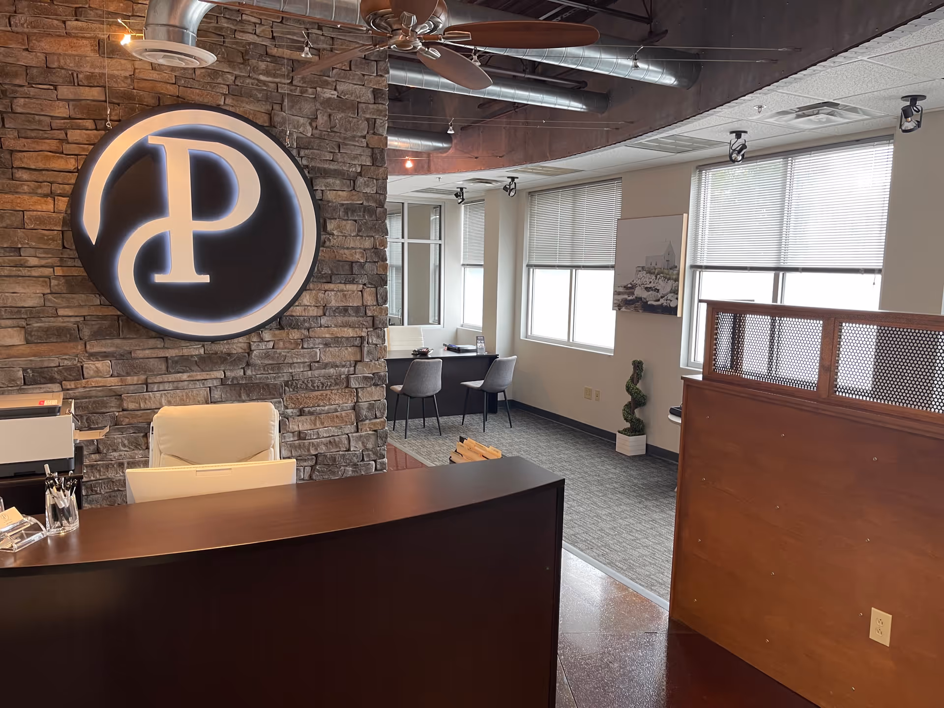 Reception area at Black Pearl Home Care with stone wall, circular logo, desk, and seating.