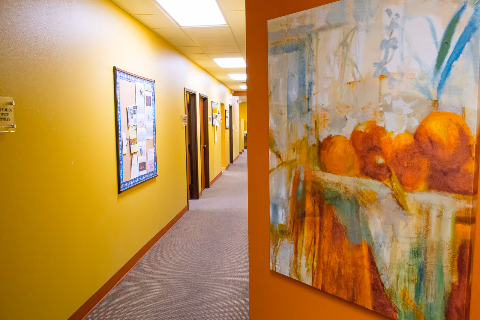 Bright hallway in a senior facility with a large colorful painting on the wall.