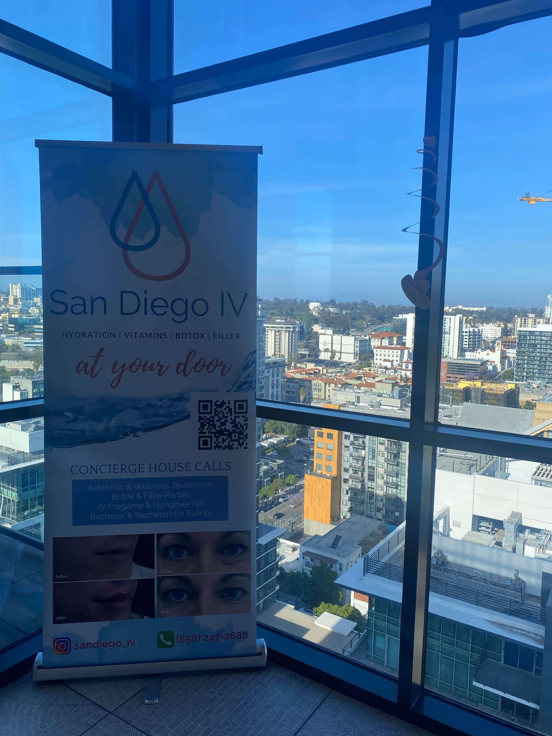 Tall banner for San Diego IV stands inside a high-rise, city skyline visible through windows.