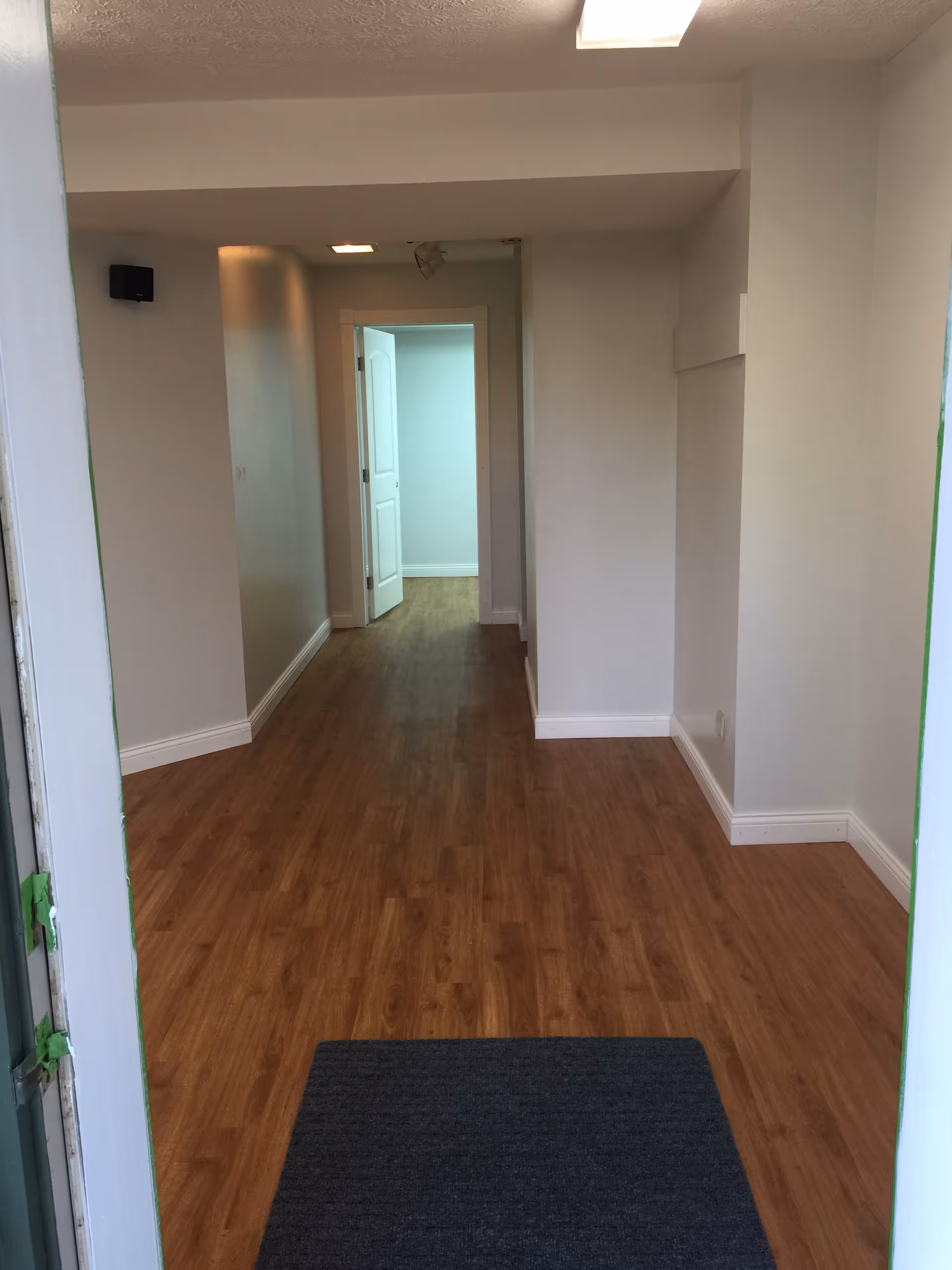 Empty interior hallway with wooden flooring and several doors in a care facility.