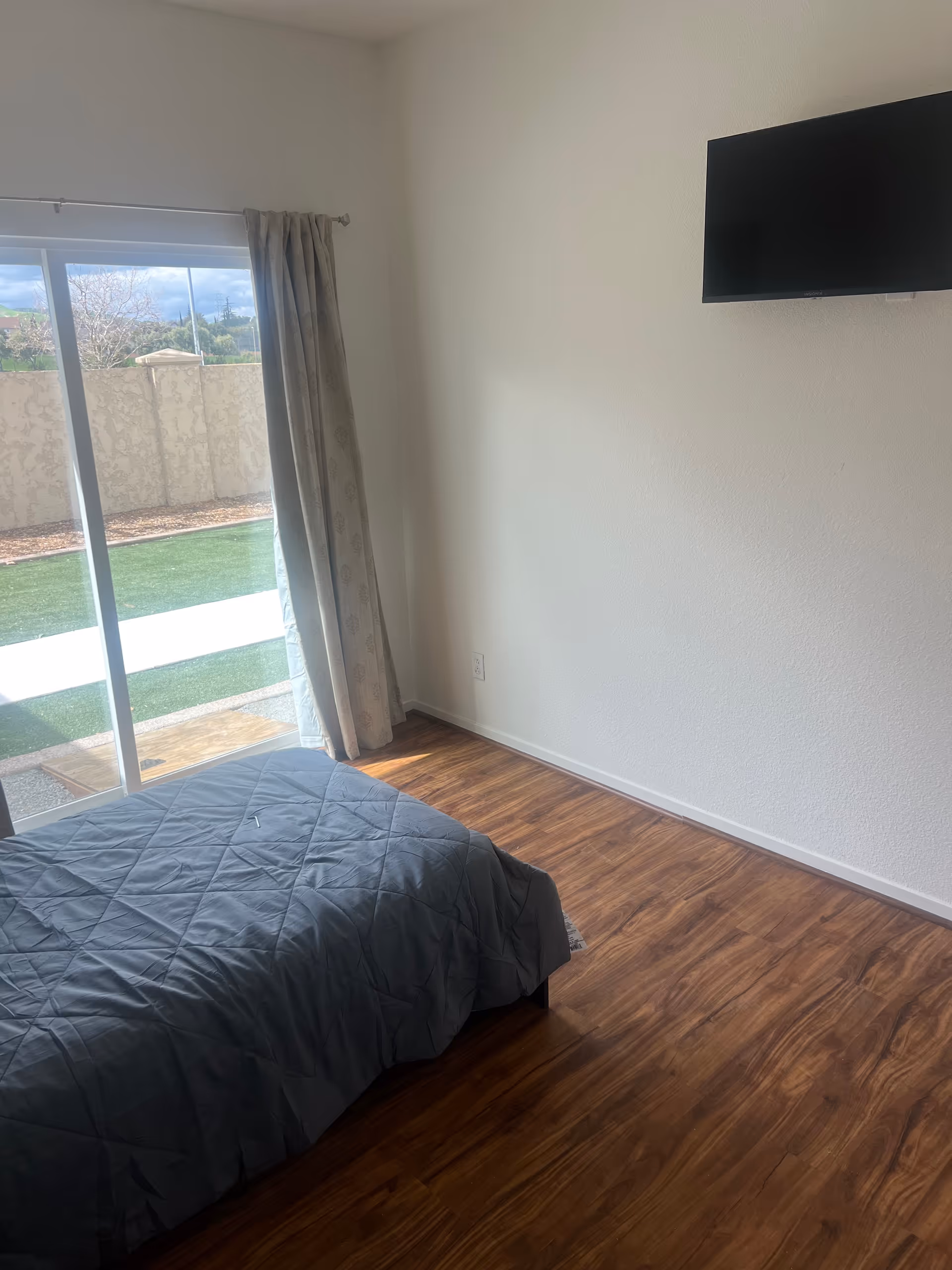 Bedroom with a bed, sliding glass door to outdoors, and a wall-mounted TV.
