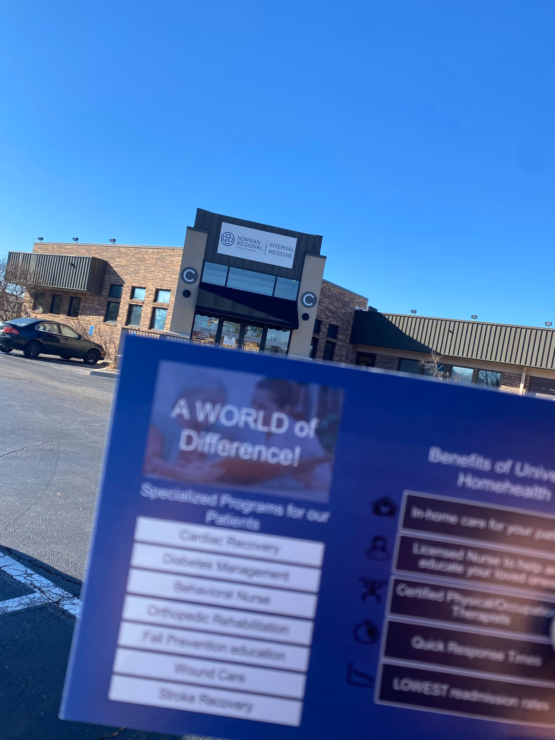 Clear blue sky over a brick medical building with a storefront, foreground shows a blue flyer.