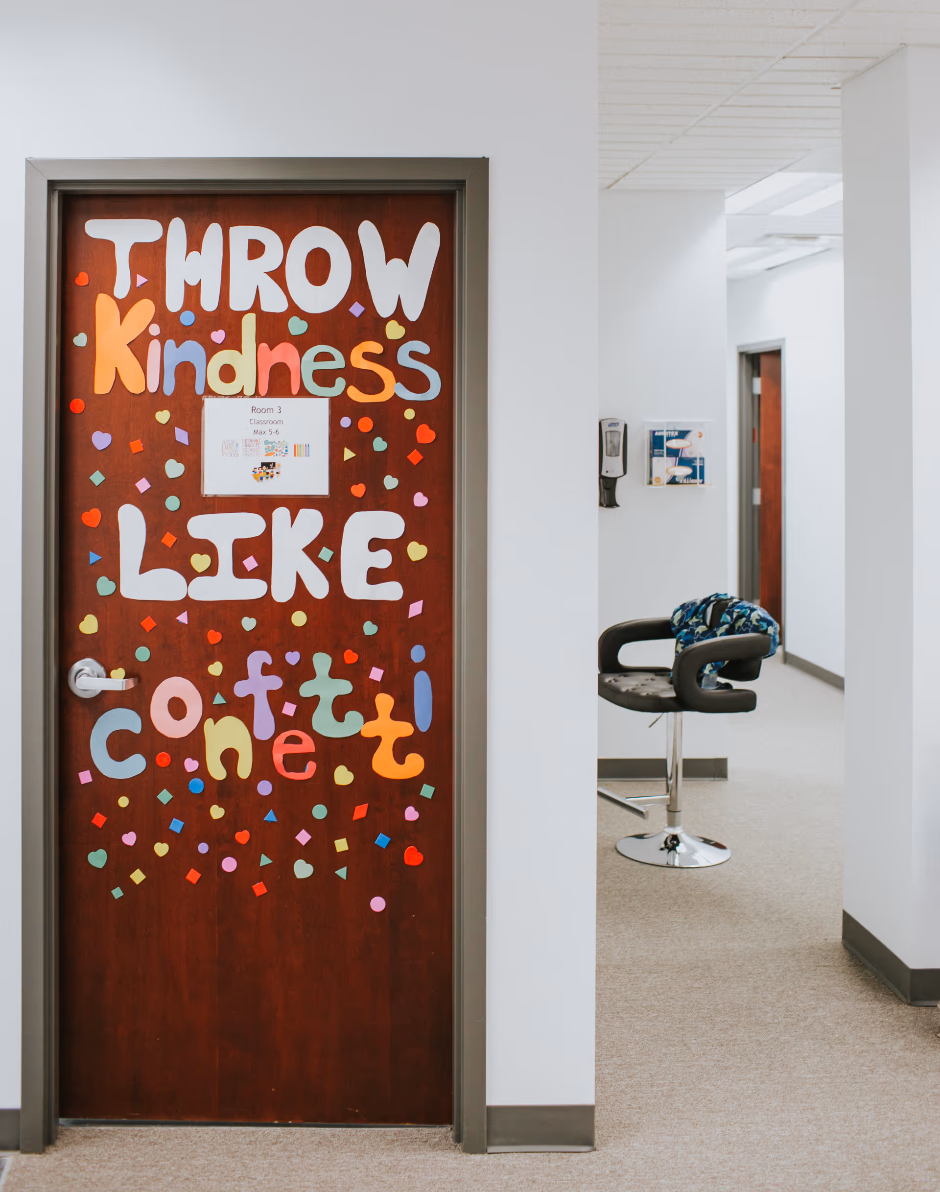 Interior hallway with a decorated door reading 'Throw Kindness Like Confetti'.