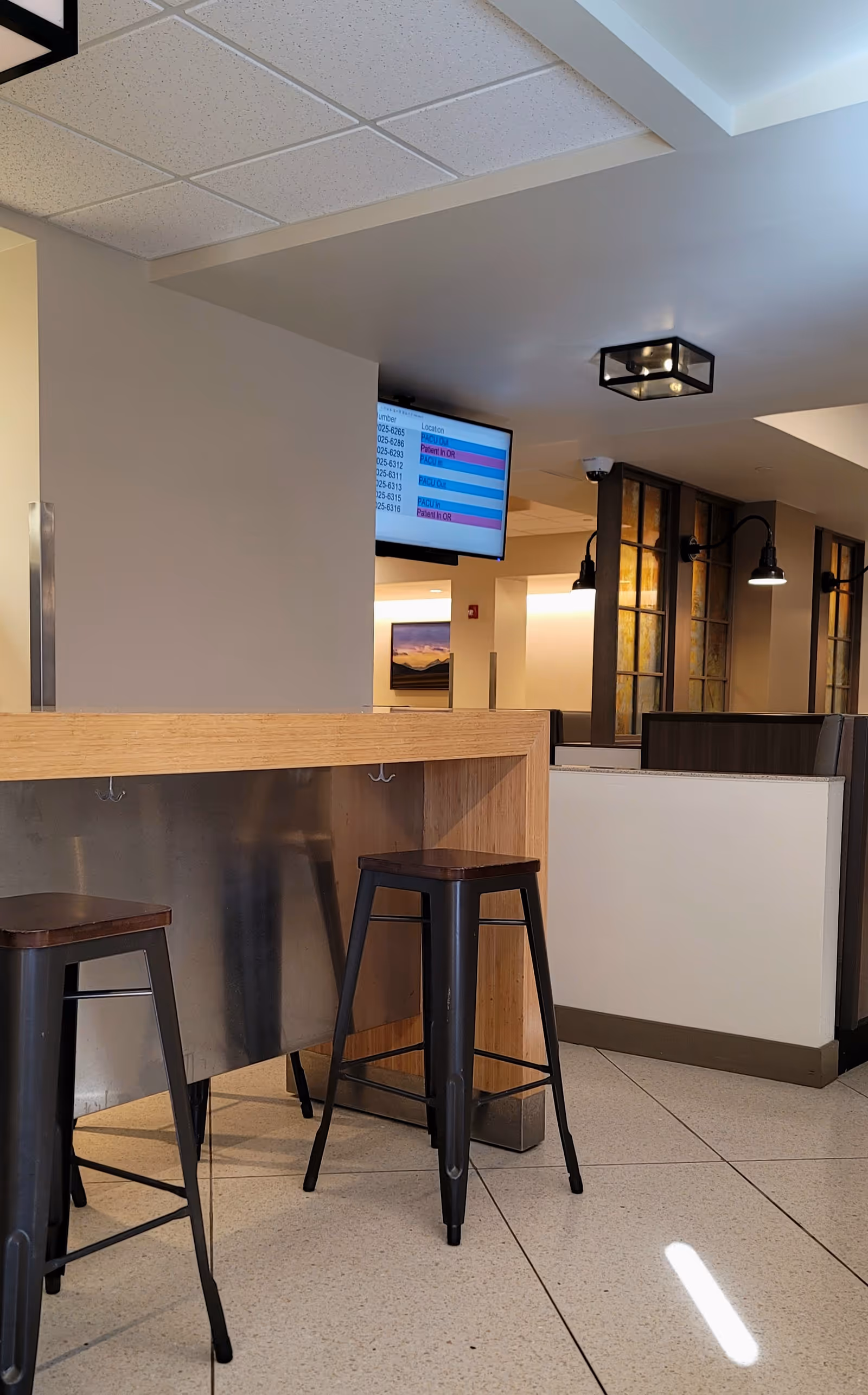 Indoor dining area featuring a wooden counter with metal stools and booths.
