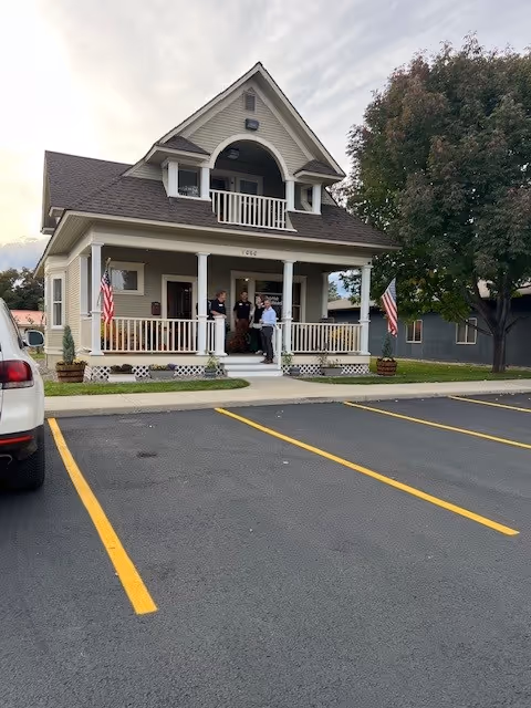 Front view of a Home Instead senior living facility with people on the porch.