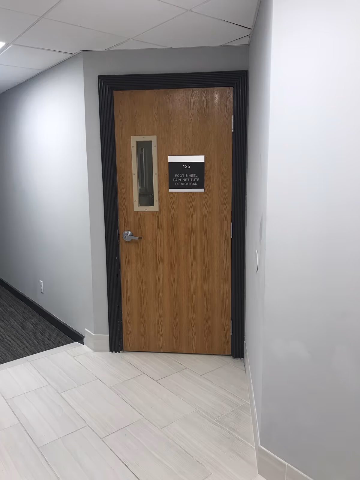 Interior hallway with a wooden door labeled Foot & Heel Pain Institute of Michigan.