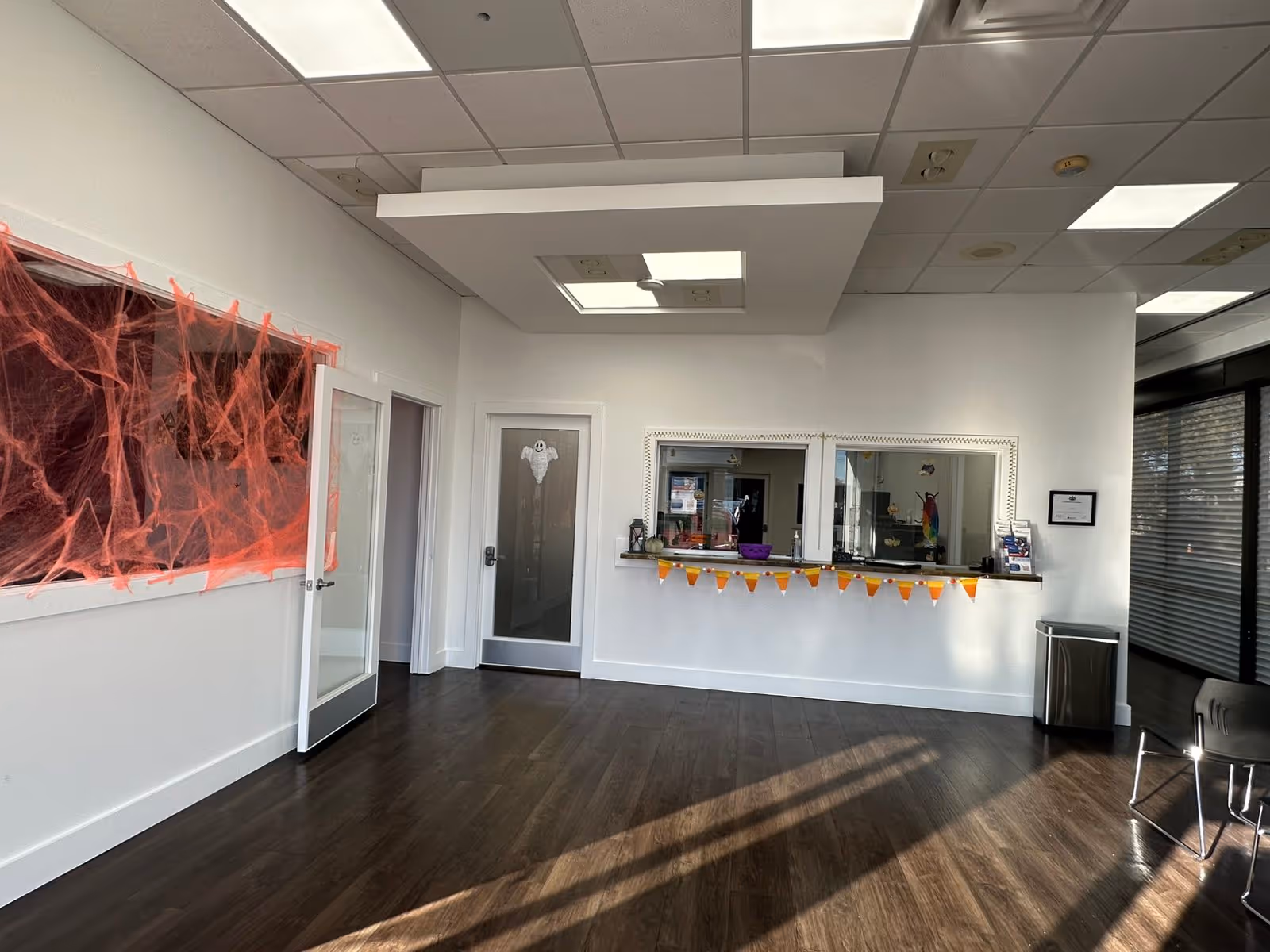 Interior reception area with a counter, Halloween decorations, and empty chairs along the wall.