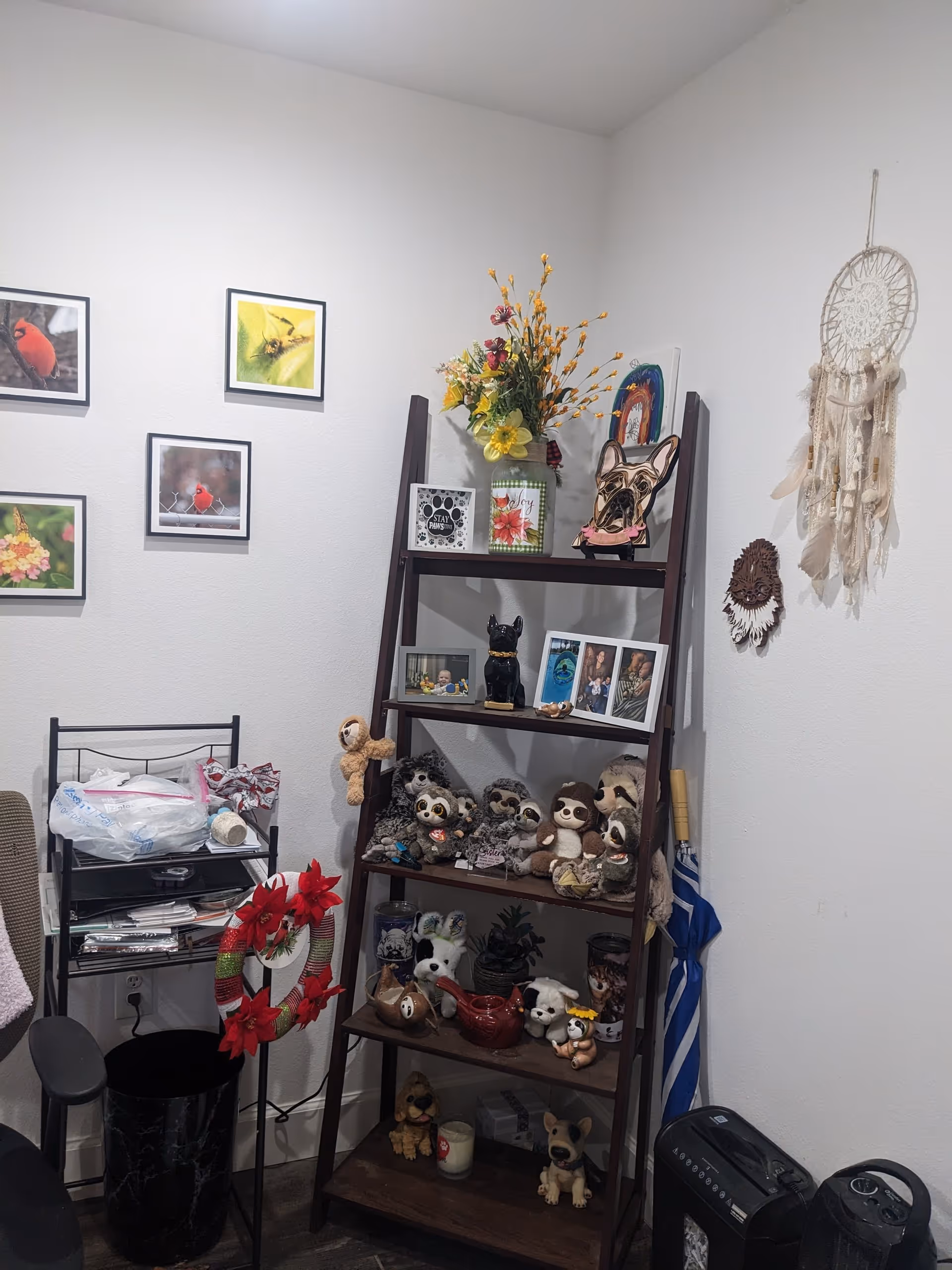 A cozy corner of a room with a dark shelf filled with stuffed animals and photos.
