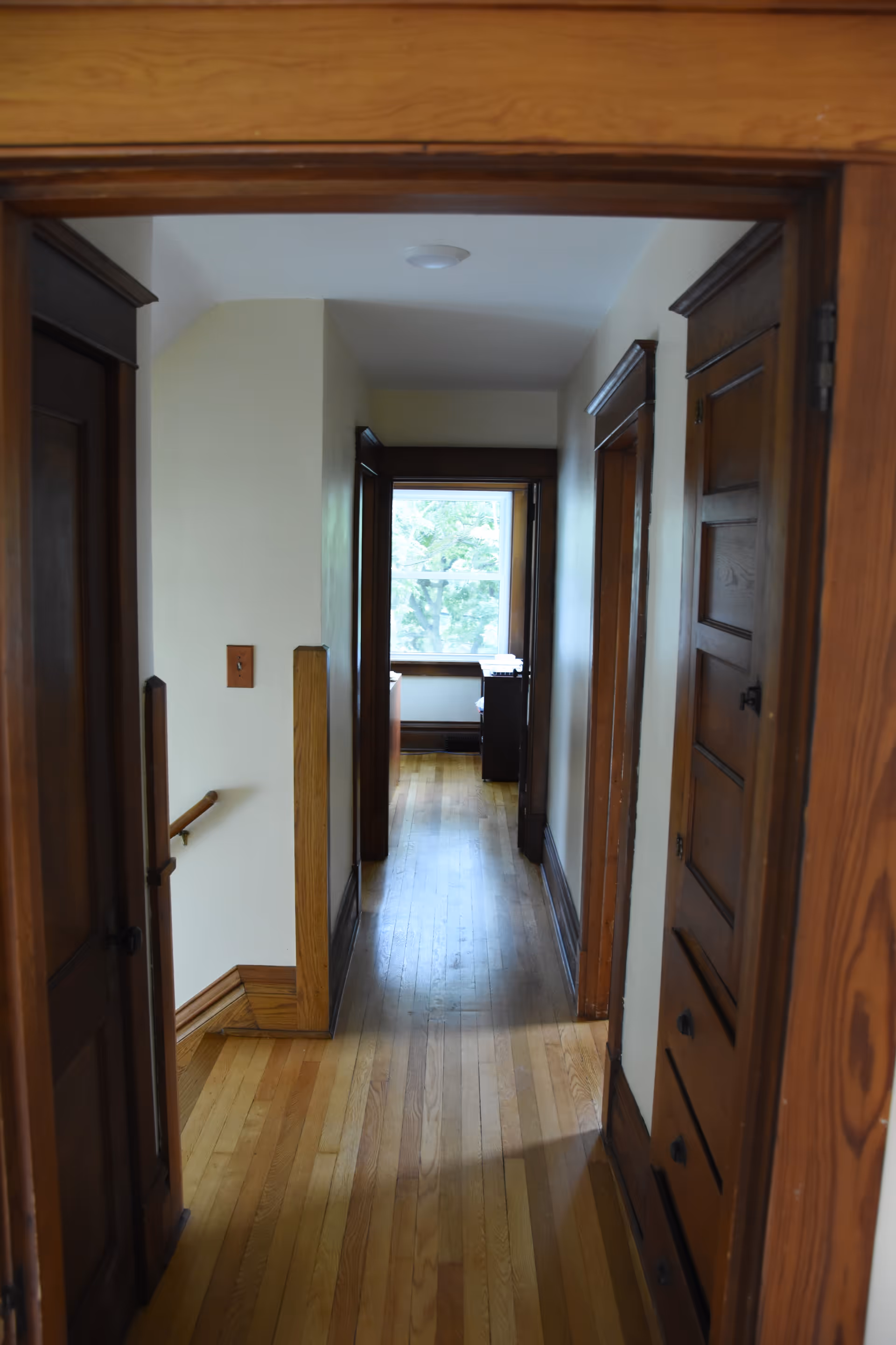 A wooden hallway in a senior living facility with closed doors and natural light.