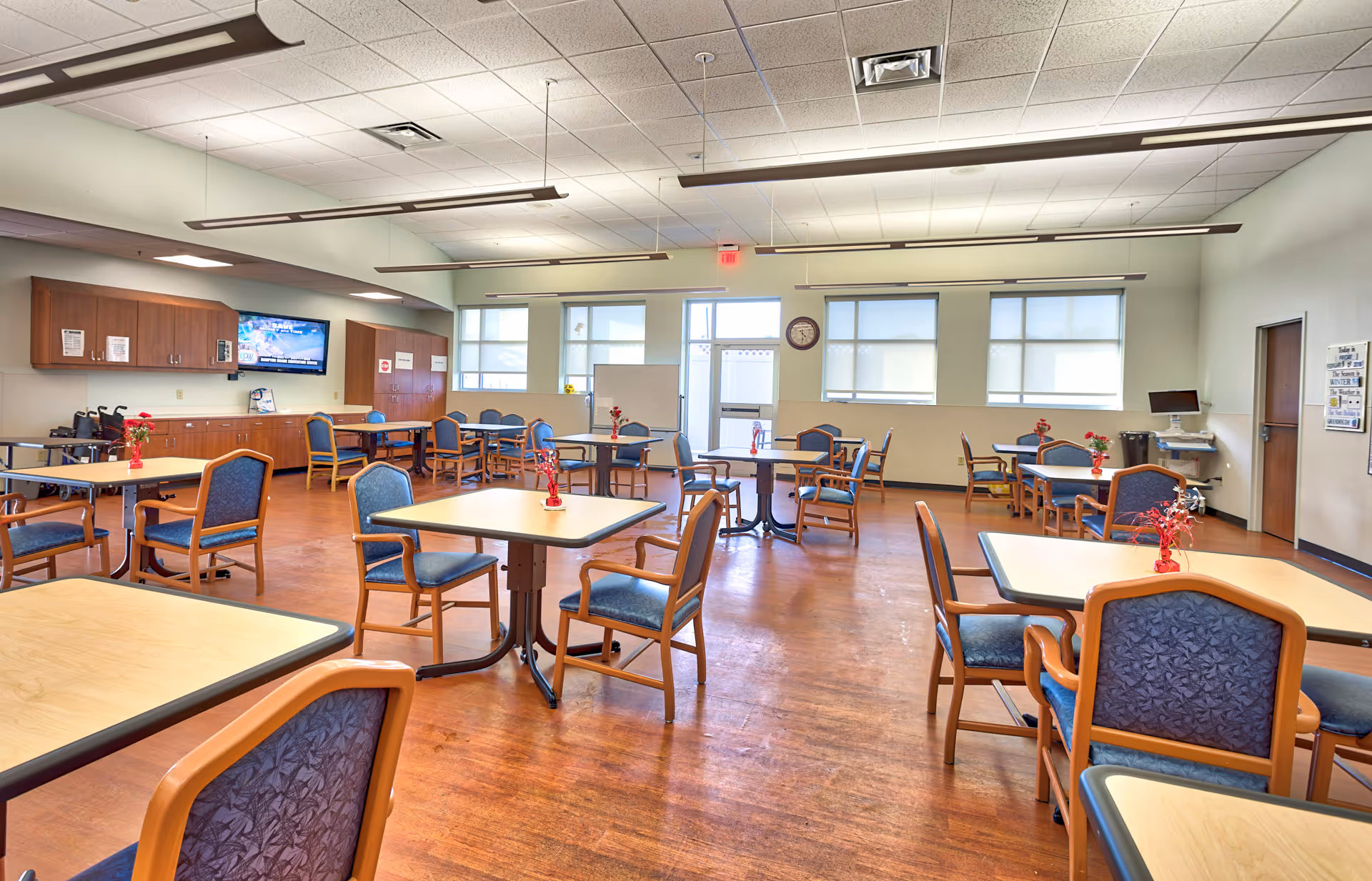 Spacious, well-lit communal dining area with multiple square tables and blue chairs.