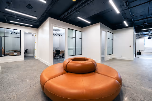Spacious modern interior with circular orange lounge seating in white-walled office suites.