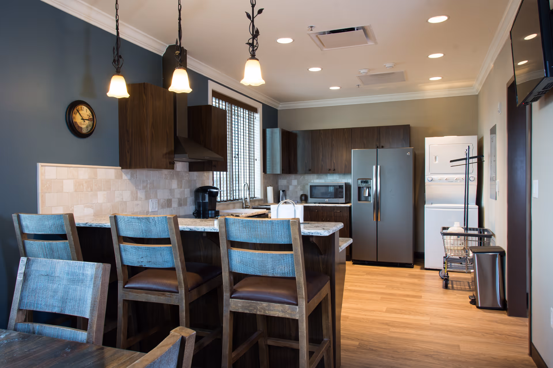 Modern kitchen with island, bar stools, and stainless appliances in a senior living facility.