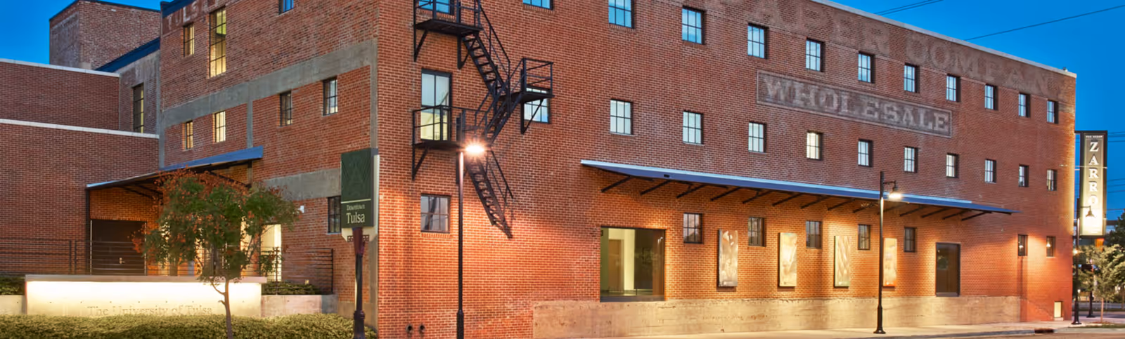 Brick building with 'Wholesale' sign, street lamps, and a small tree.