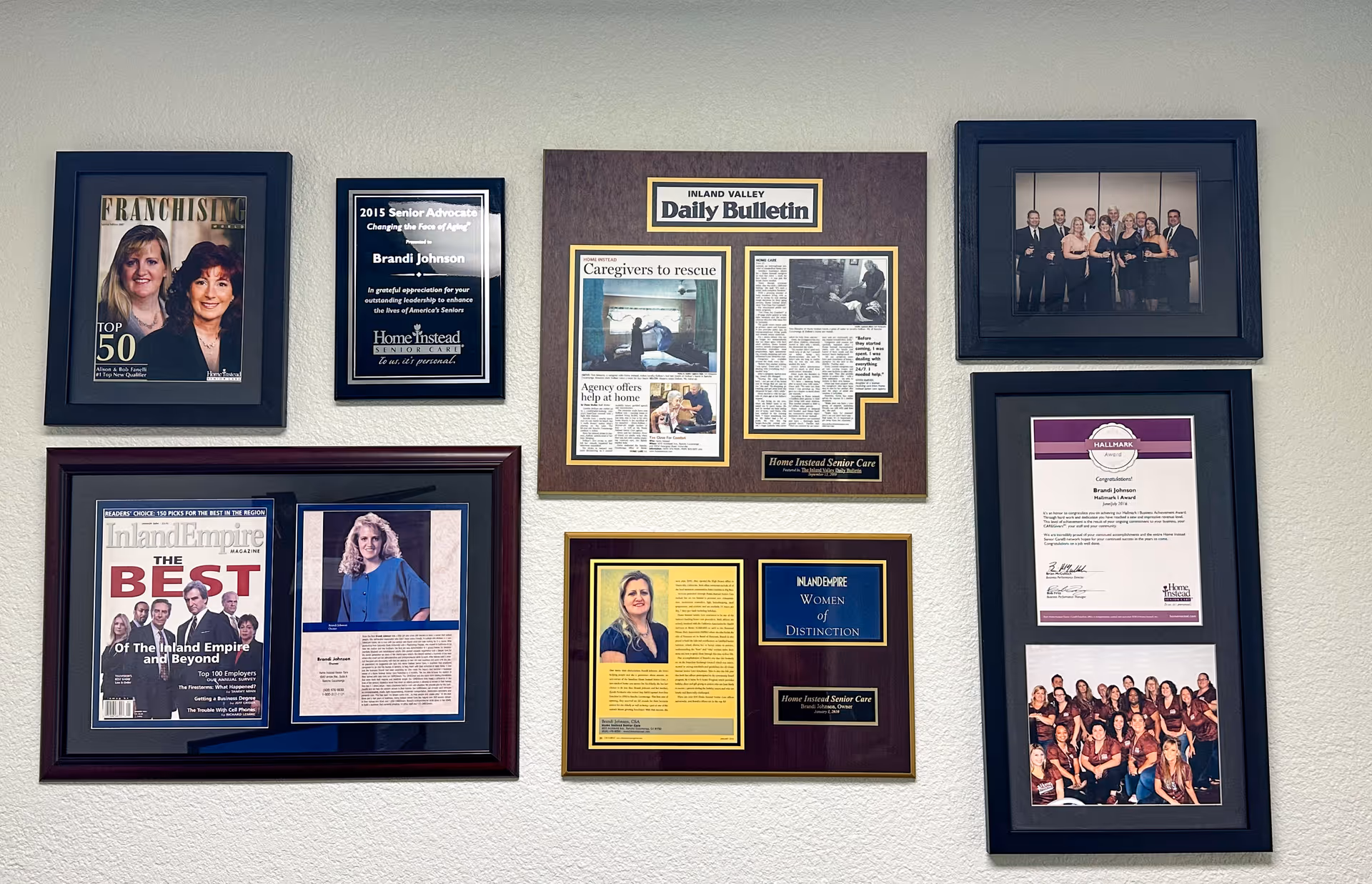 Wall gallery of framed awards, clippings, and photos in an interior hallway.