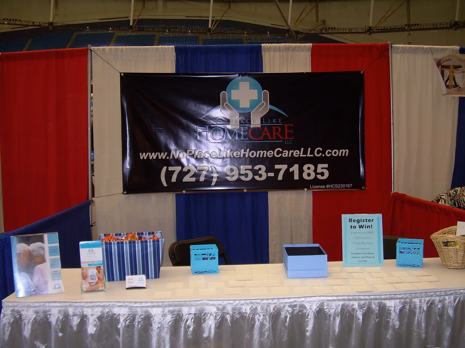 Indoor convention booth featuring a No Place Like Home Care banner and information table.