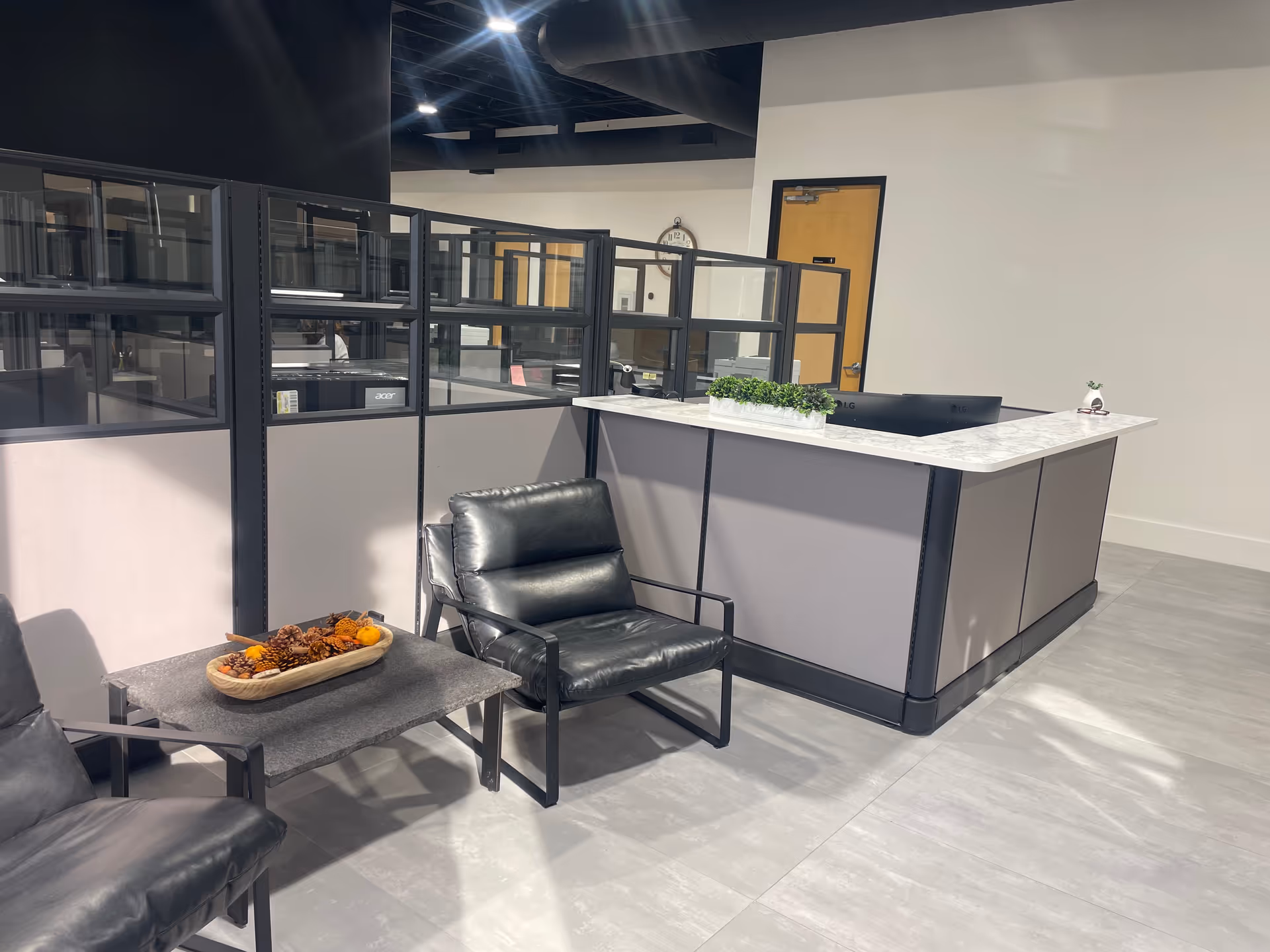 Modern reception desk with marble top and black lounge chairs in a lobby.