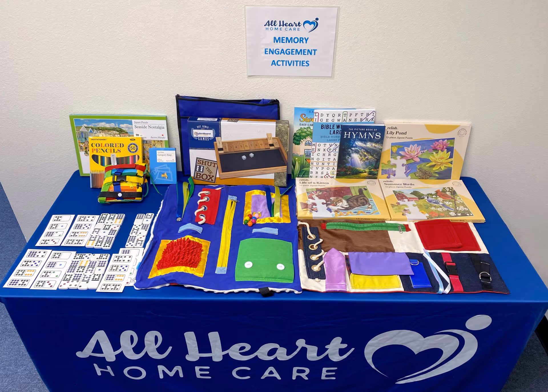 Table with a blue cloth displays memory engagement activities and books in a senior facility.