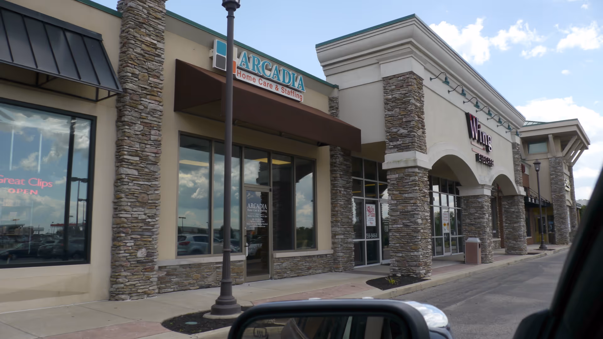Exterior view of a shopping plaza featuring Arcadia Home Care & Staffing storefront and stone columns.