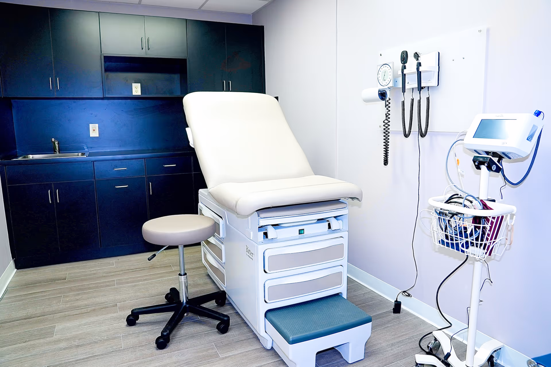 Medical examination room with a reclining chair, medical equipment, and cabinets.