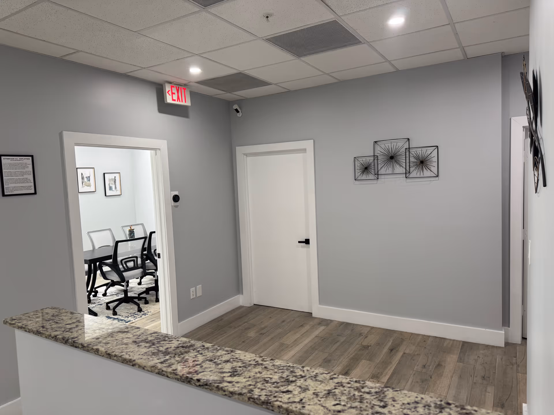 Light gray hallway with granite counter and meeting room visible through doorway.
