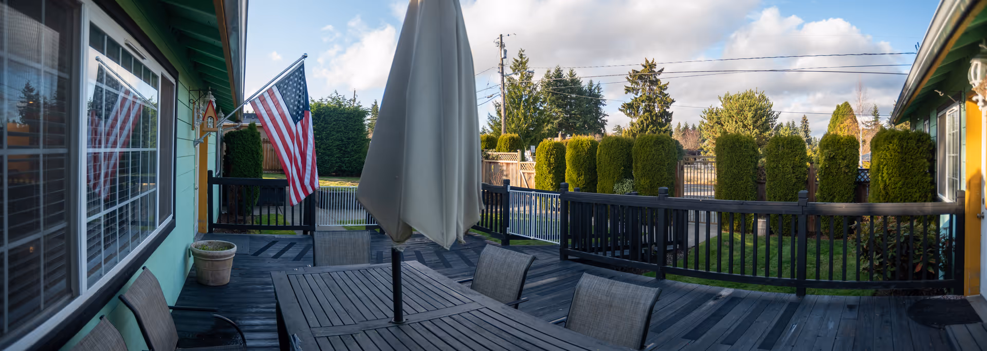 Outdoor patio at Golden Care, with table, chairs, umbrella, American flag, and manicured hedges.