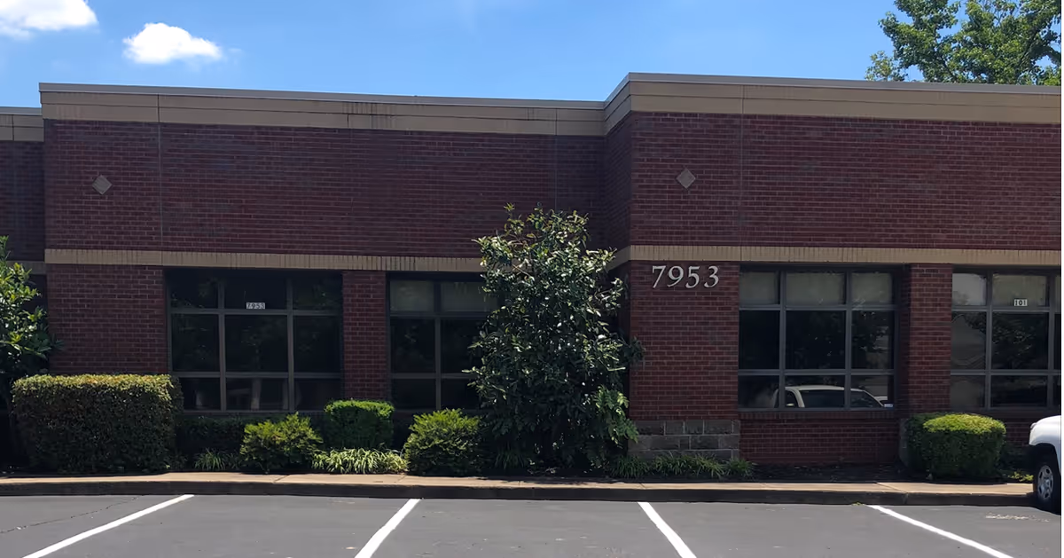 Brick exterior of Caris Healthcare facility with windows, landscaping, and a parking lot.