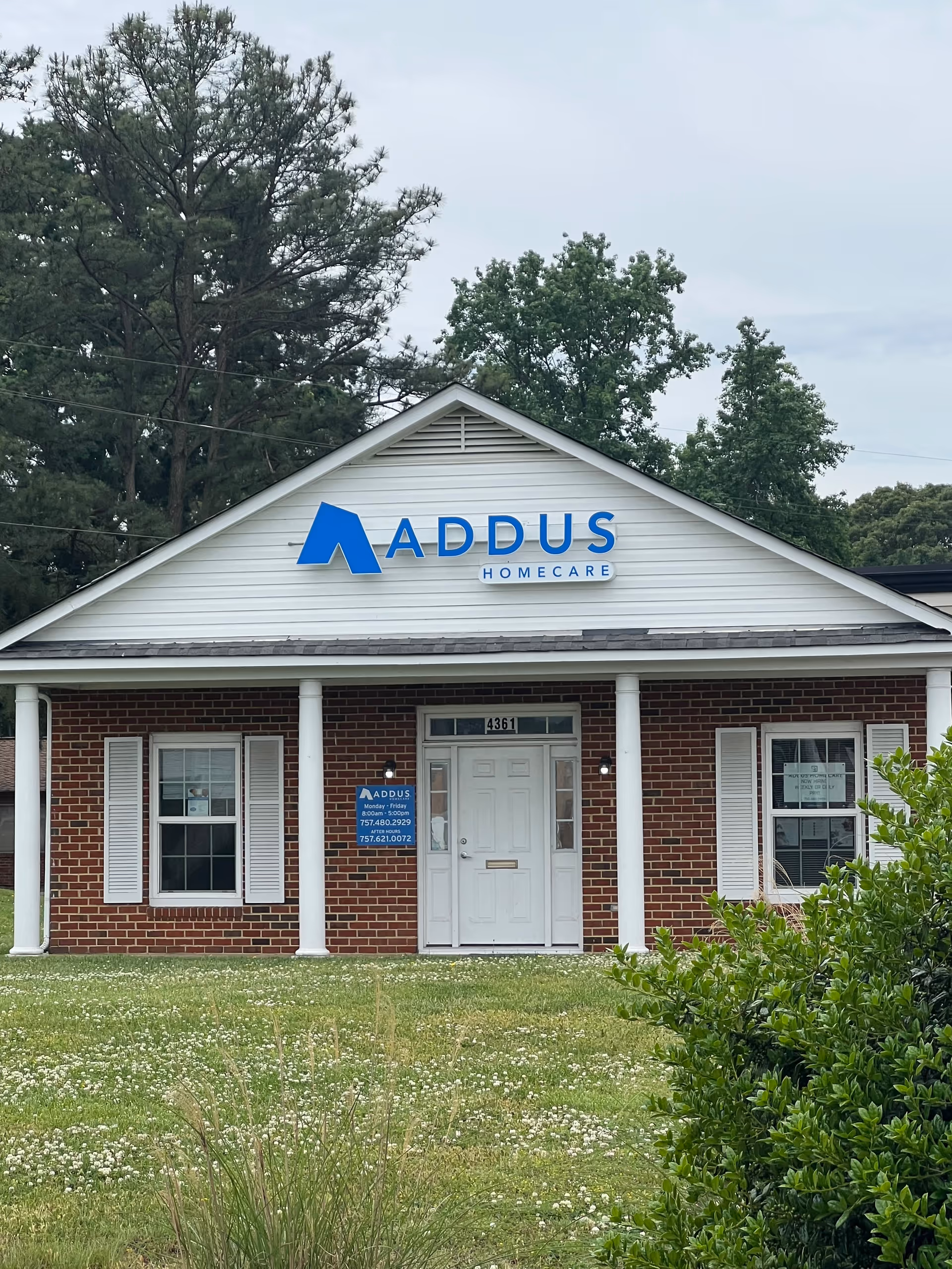 Brick building with white columns and a large blue Addus HomeCare sign.