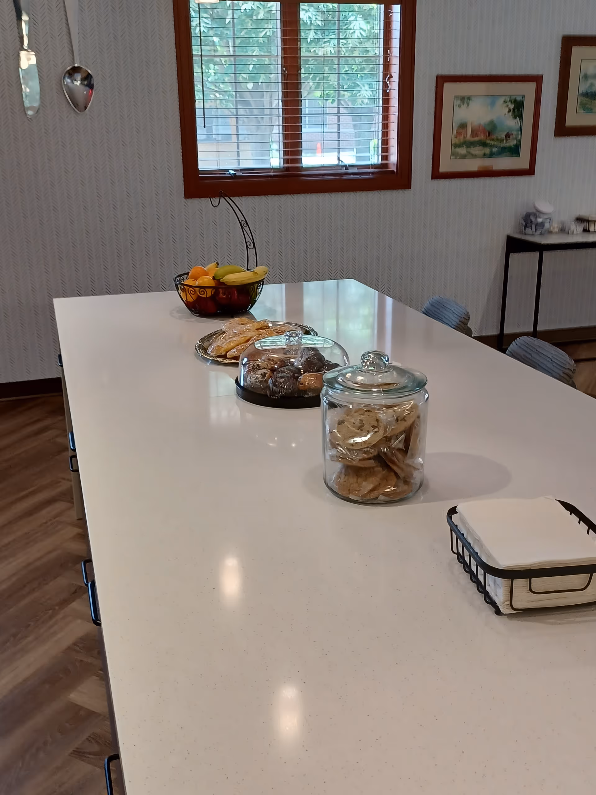 Bright kitchen island with fruit, cookies, and pastries in a senior living facility.
