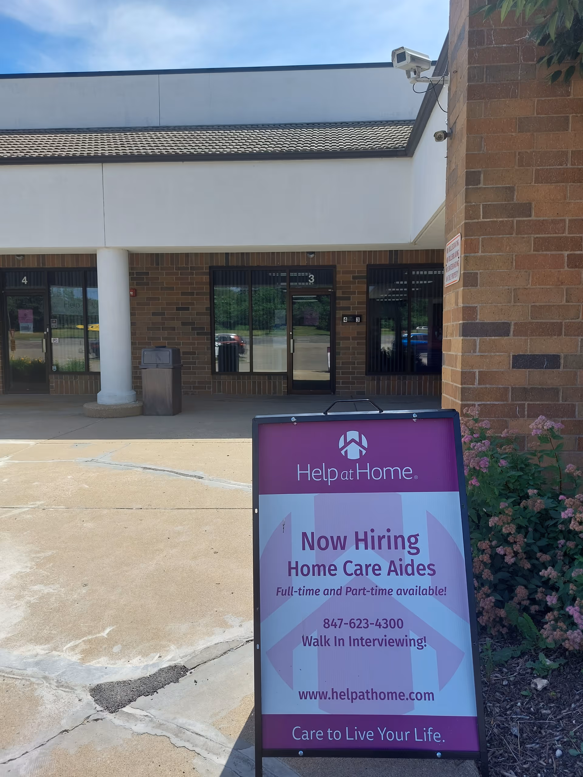 Exterior view of Help at Home facility with a hiring sign in the front area.
