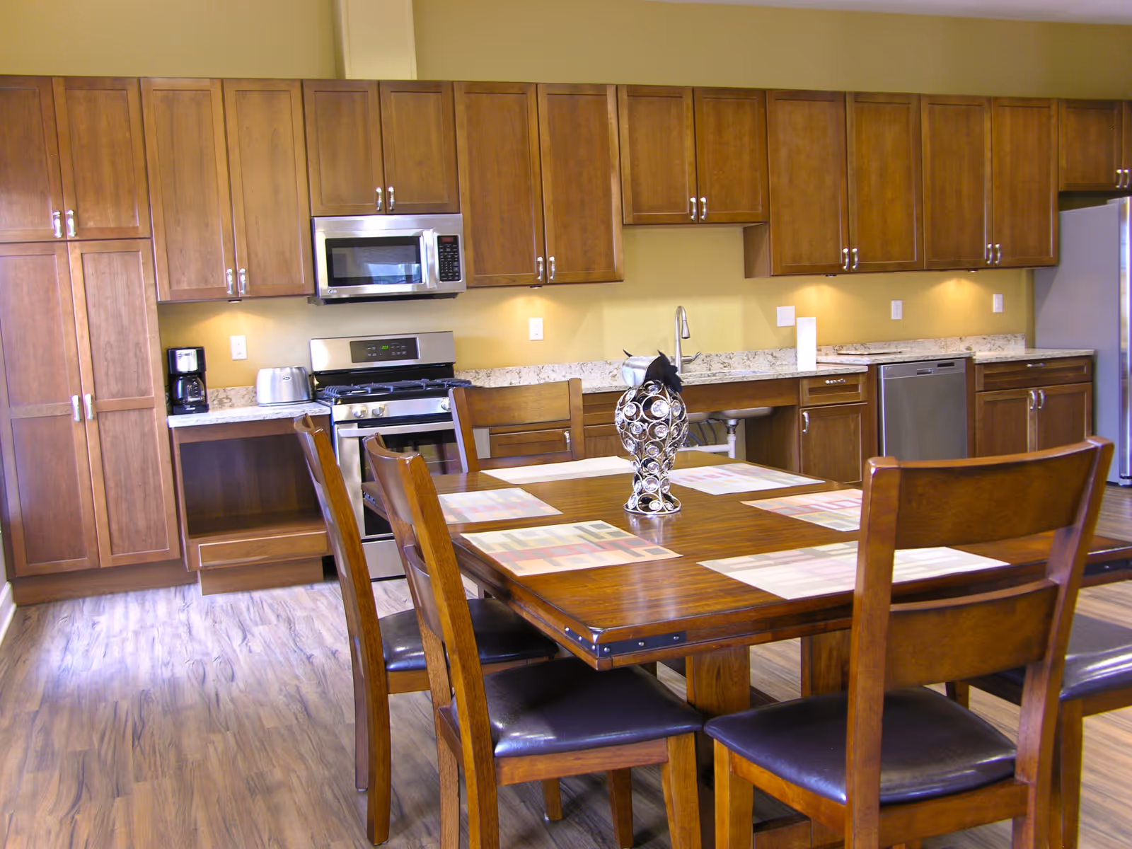 A spacious kitchen with wood cabinetry, stainless appliances, and a dining table.
