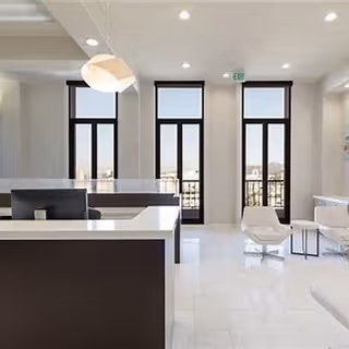 Bright modern facility lobby with a reception desk, white surfaces, and tall windows.