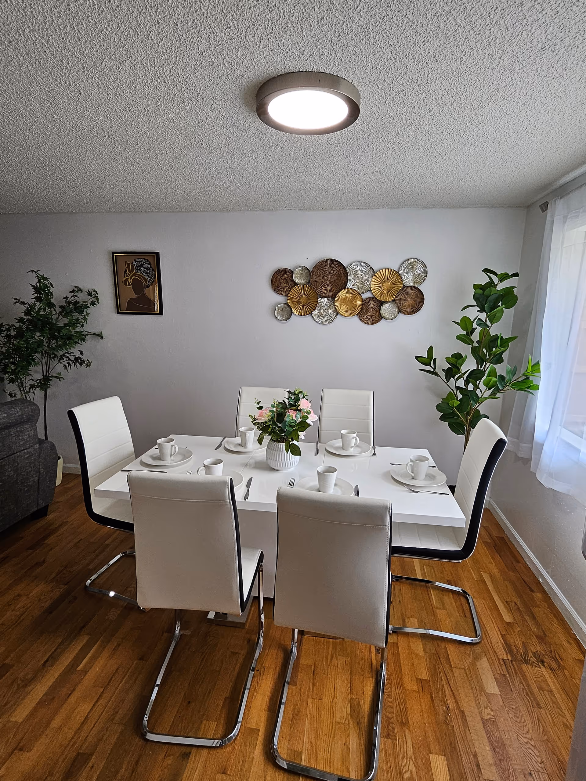 White dining table set with plates and cups in a bright dining room.