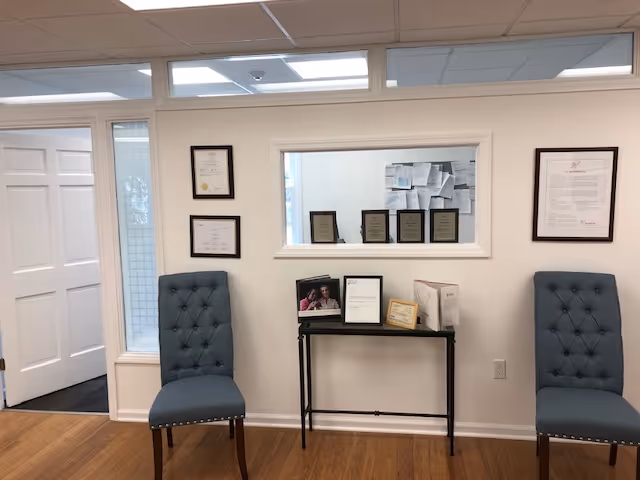 Lobby area with two blue tufted chairs and a console table against a wall.
