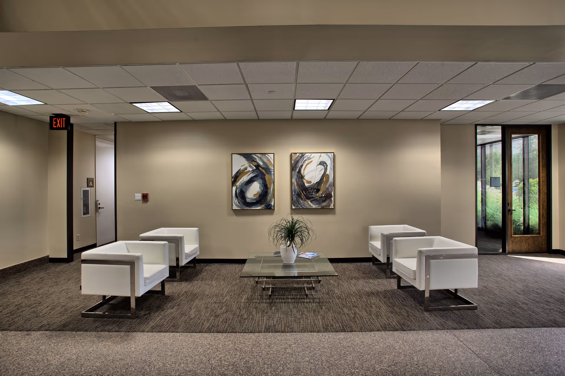 Modern lobby with six white chairs around a glass coffee table and abstract wall art.