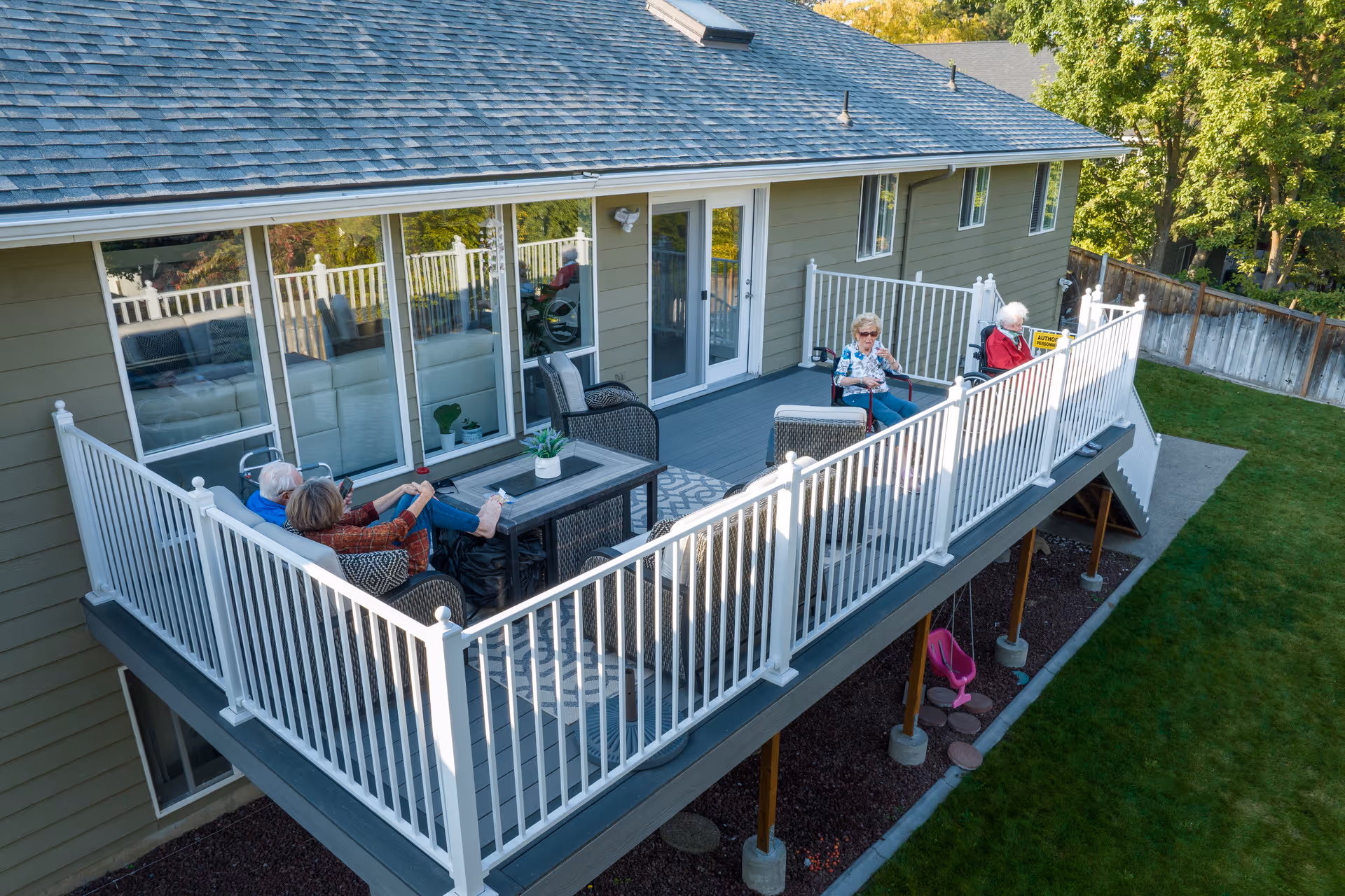 Senior residents lounge on a large outdoor deck with chairs.