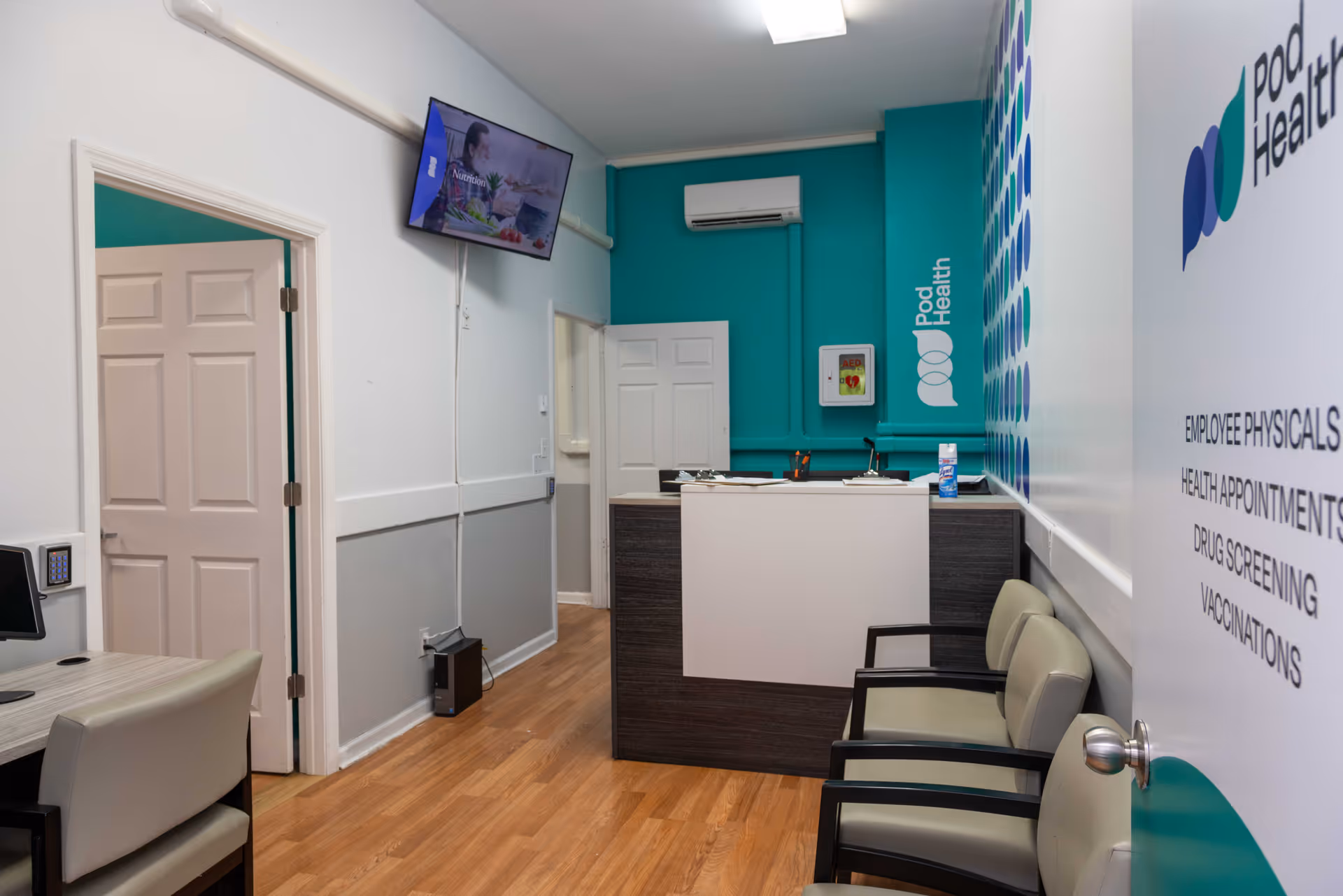 Reception area inside Pod Health facility with a desk, chairs, and teal walls.