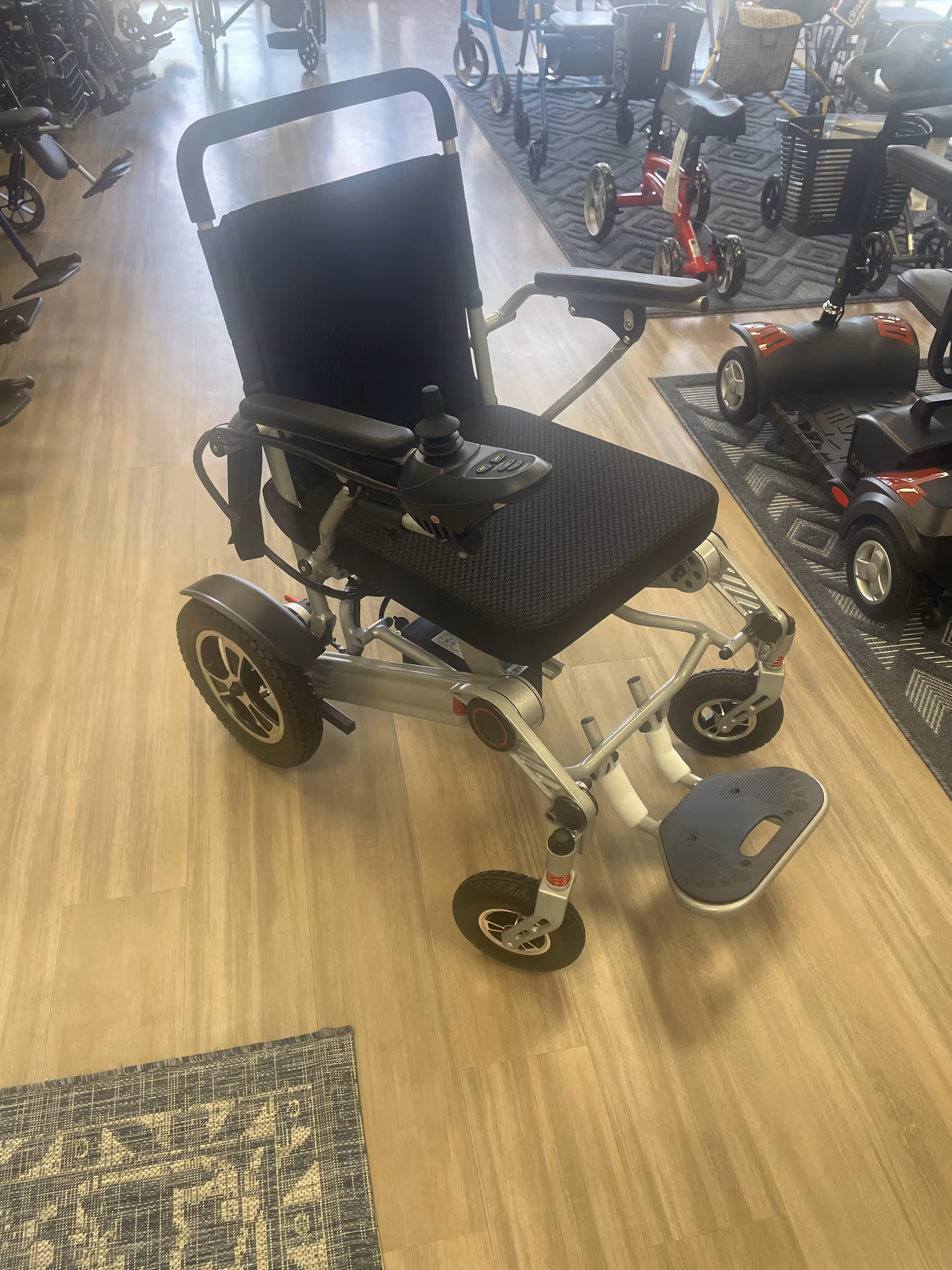 Electric wheelchair on display inside a showroom with other mobility devices.