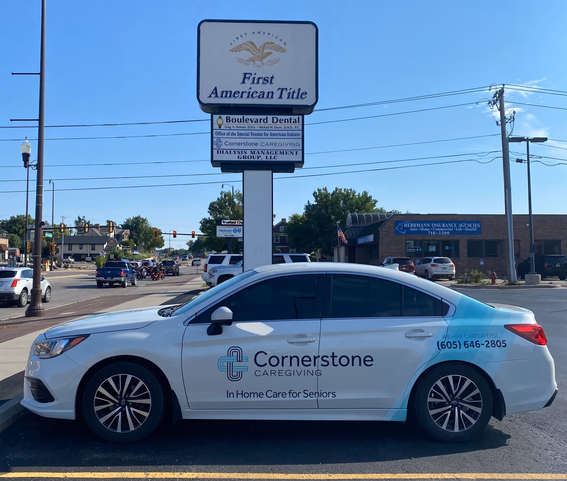 White Cornerstone Caregiving car parked on a street beside a large sign