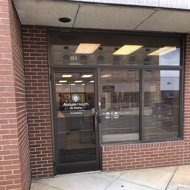 Brick exterior building with glass entrance door labeled Atrium Health At Home.