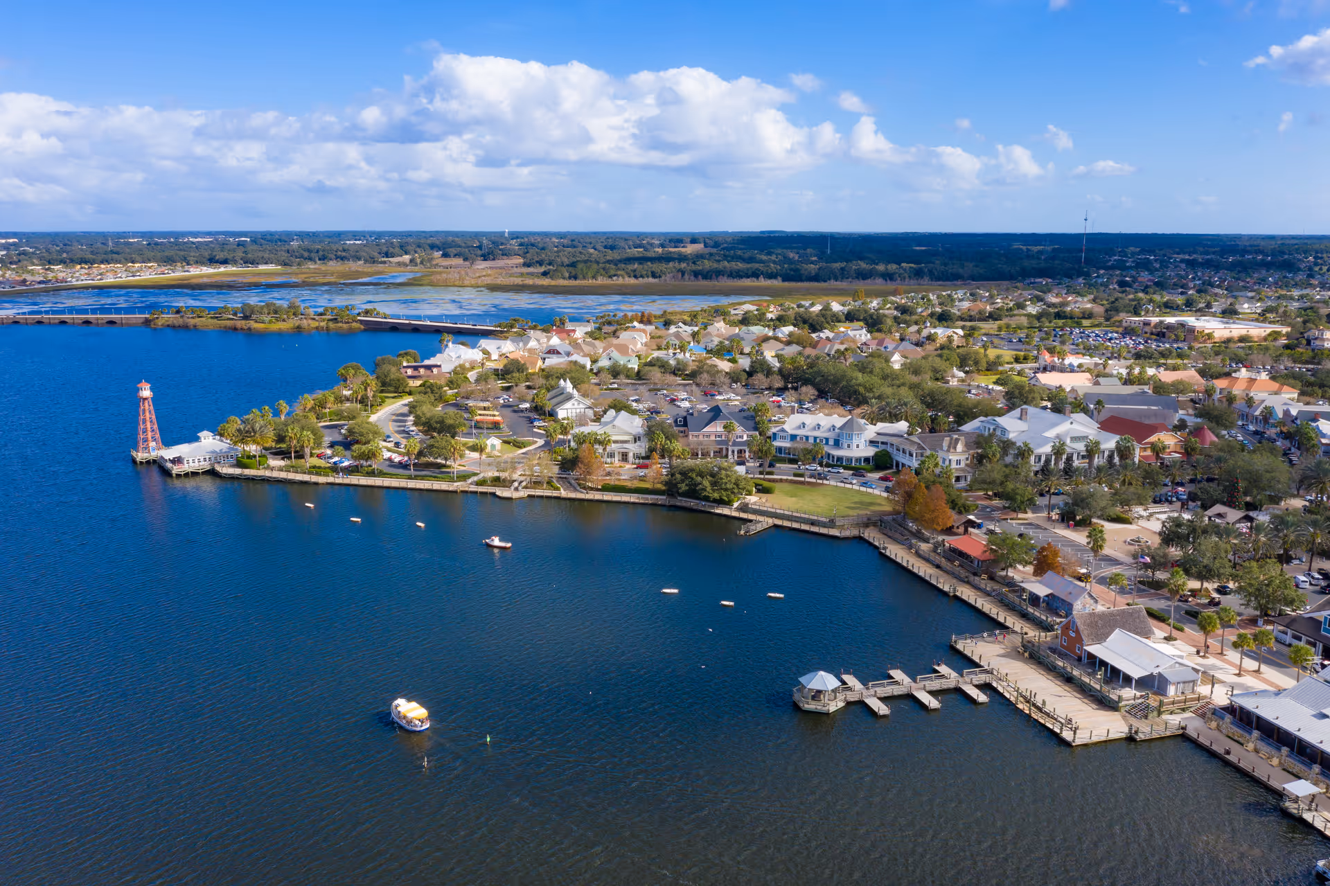 Aerial view of a lakeside town with docks, houses, and blue water.