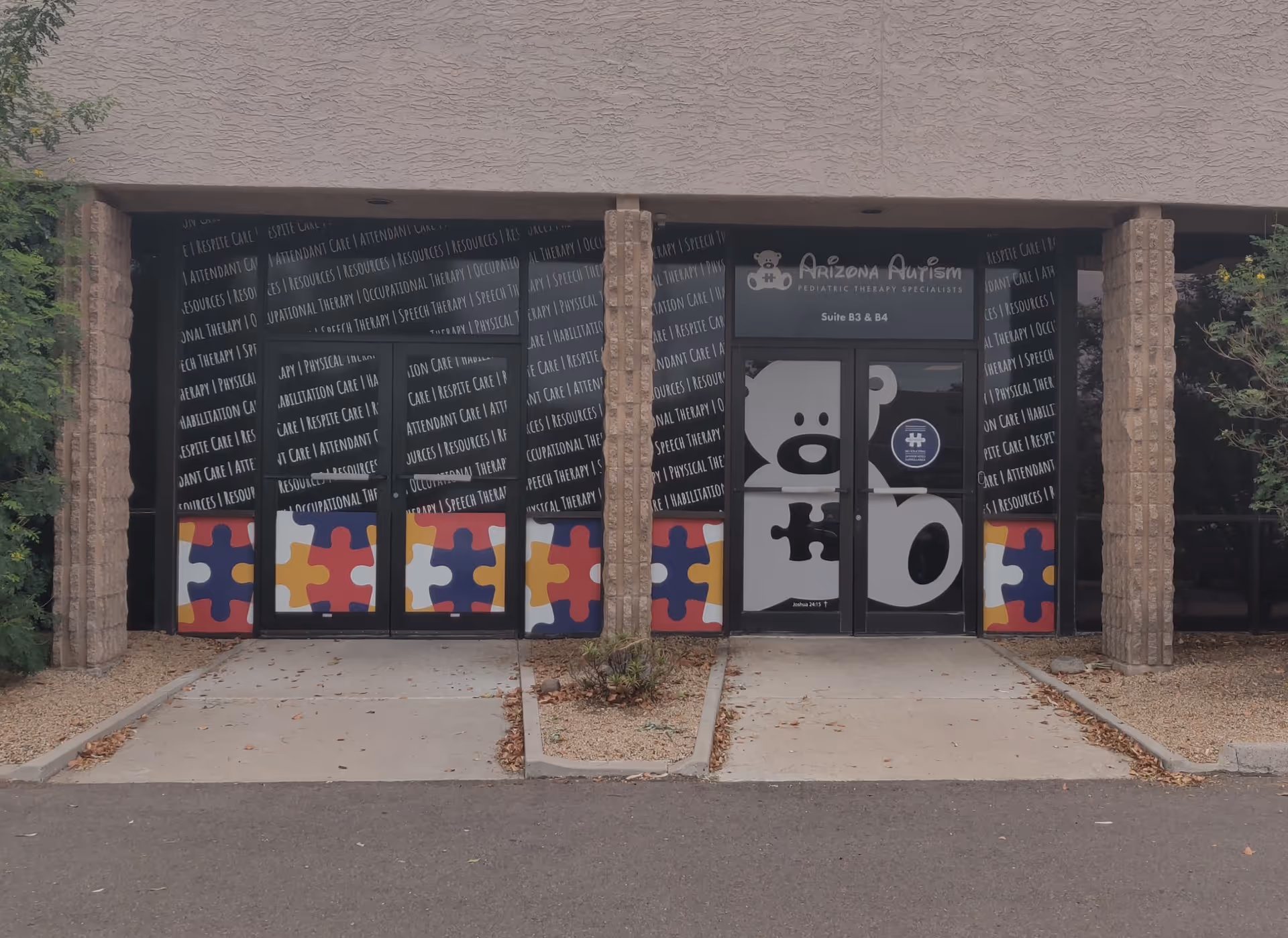 Front view of Arizona Autism facility with glass doors and puzzle-piece decor.