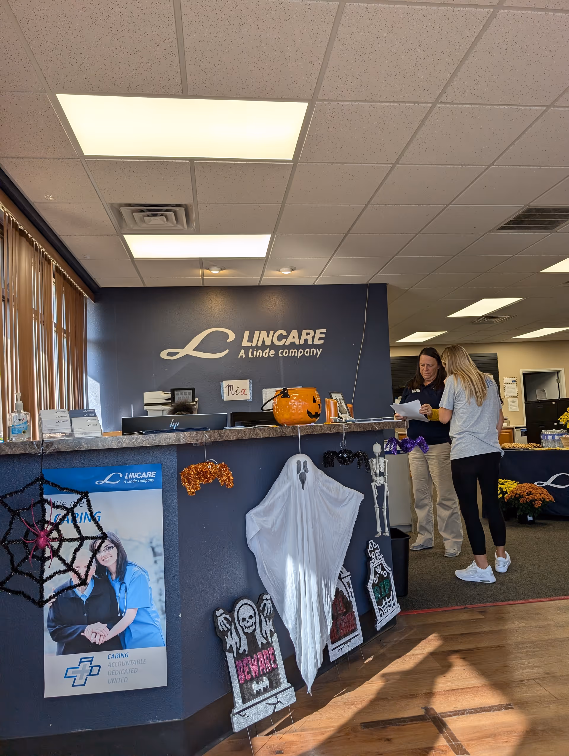 Reception area inside a LINCARE facility with two staff members at a counter.