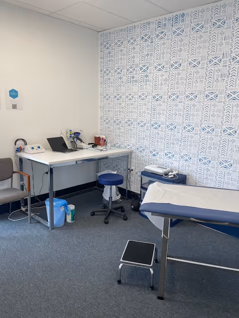 Clinic exam room in a senior facility with an examination bed and medical supplies.
