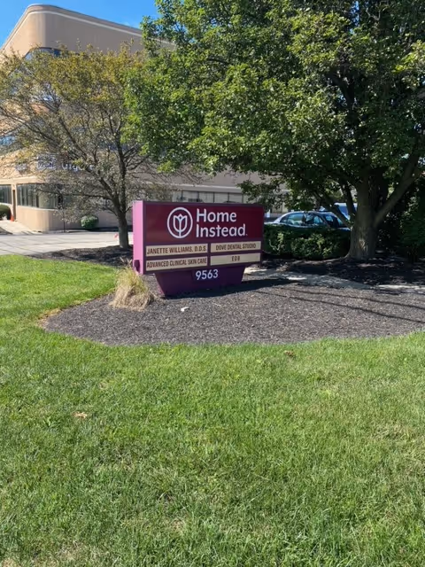 A Home Instead sign on a landscaped island in front of the facility.